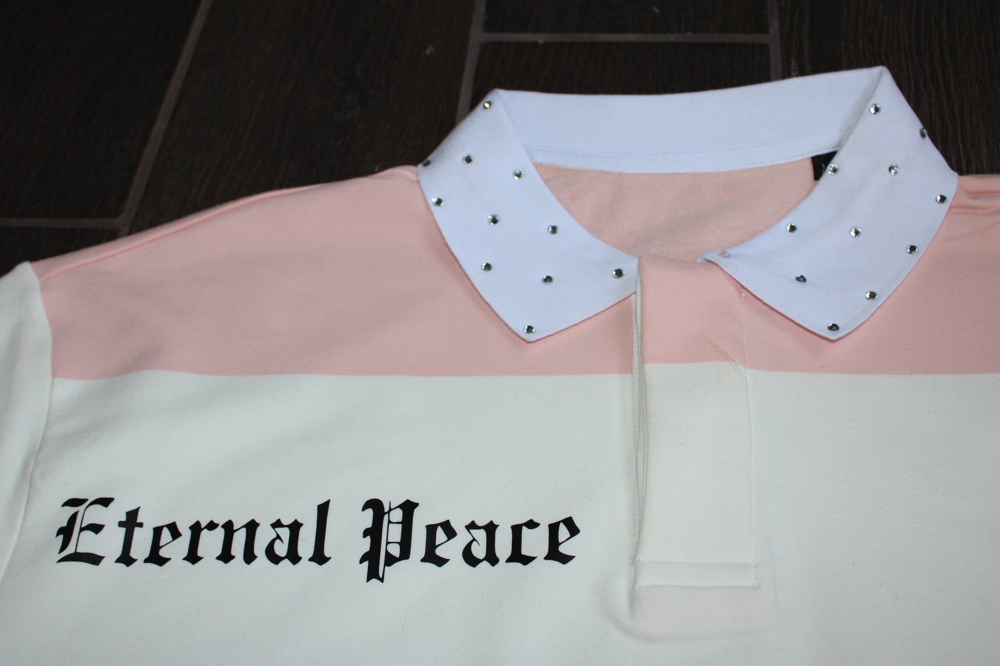 Pink and white shirt with studded collar and 'Eternal Peace' text on a dark background